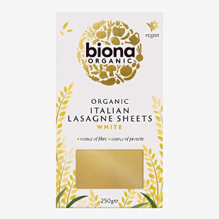 A rectangular pack shows the Biona Organic logo on a white-and-green background; a vivid photo of layered lasagne fills the front, with wheat graphics and the product name in bold green type. Clean edges, small icons and ingredient text appear along the bottom. A small green leaf sits by the corner.