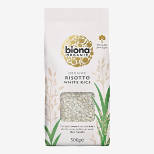A tidy photo shows six upright Biona white risotto rice packets, each in a clear-lined bag with a green Biona logo and simple white label. Short-grain white rice fills each pack; labels display organic wording and 500g weight. Clean, bright studio lighting.