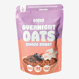 A rectangular carton and scattered single-serve pouches show the Oatco logo on warm brown and cream backgrounds. Chocolate swirls, cocoa nib illustrations and whole oat imagery decorate the front. Panels of small text and icons line the sides.