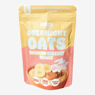 OATCO Overnight Oats Banana Biscuit Boost packages appear in a photo: bright yellow and cream tubs with bold logo, banana and biscuit graphics, and oat clusters on the label. Clear lids reveal creamy oat texture with small banana pieces; multiple tubs sit stacked together.