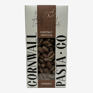 A 250g Cornwall Pasta Co packet labeled Organic Chestnut Gnocchi shows the brand logo and product name on warm, earthy packaging with seasonal Christmas motifs—subtle holly and snowflake graphics—and a clear window revealing small chestnut-coloured gnocchi shapes.