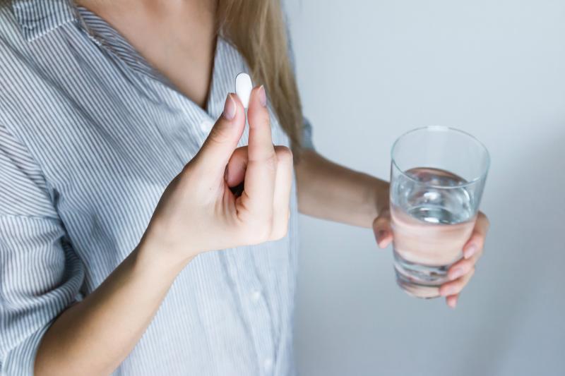 girl holding pain killer and water
