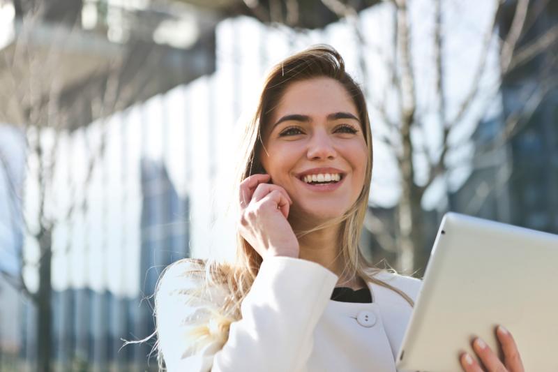 business woman smiling holding tablet outside