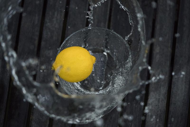 lemon being dropped in glass of water