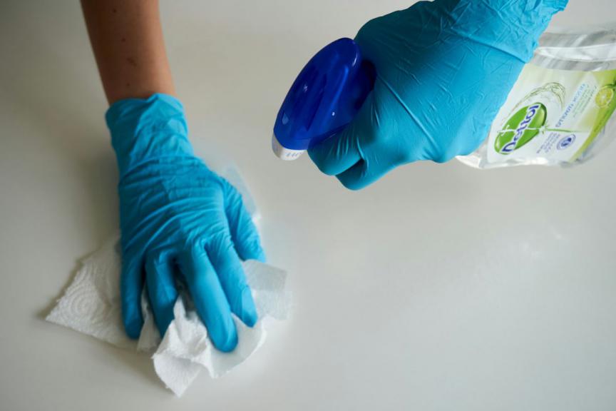 Image of surfaces being wiped down with Dettol spray. 