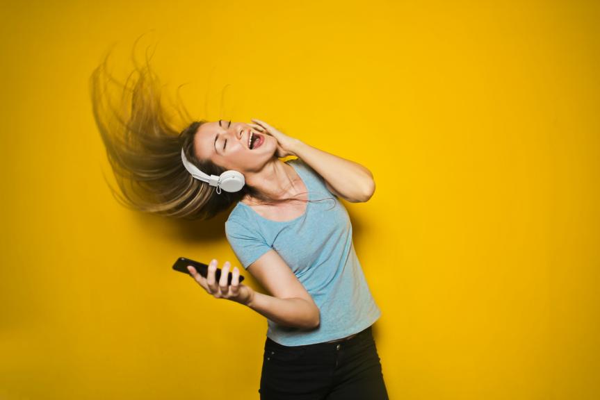 Girl Flipping hair with Headphones on Orange Background