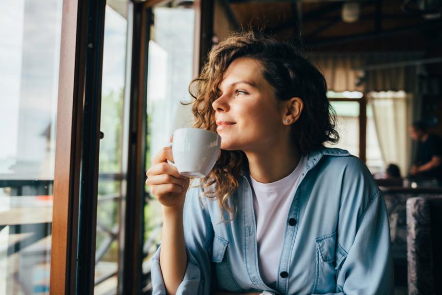 Woman sipping coffee looking out of window 