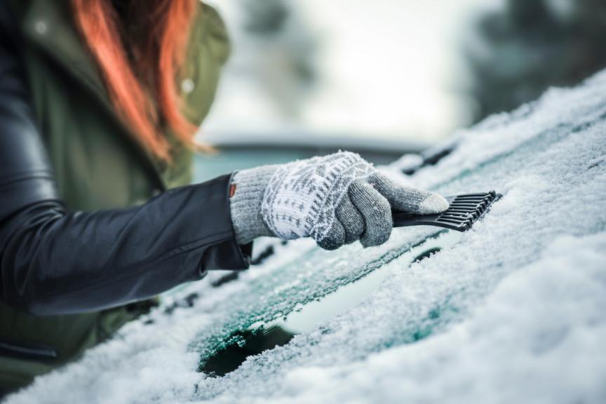 Person scraping ice off their car. 